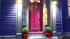 A blue building with a red door, two potted plants on the steps, and an American flag. - Moroccan Boutique Guest House (Boston)