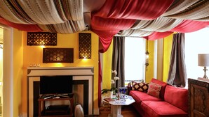 A living room with a red sofa, a fireplace, and a table with decorative items. - Moroccan Boutique Guest House (Boston)
