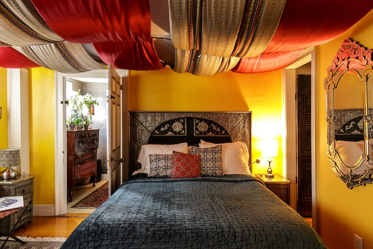 A bedroom with a bed, a nightstand, a dresser, and a mirror.
