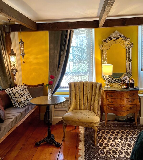 Una habitación con sofá, sillón, mesa, cómoda y espejo.