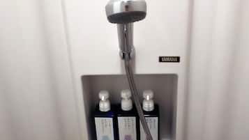 A shower area with a Yamaha-branded showerhead and three bottles of shampoo or conditioner.