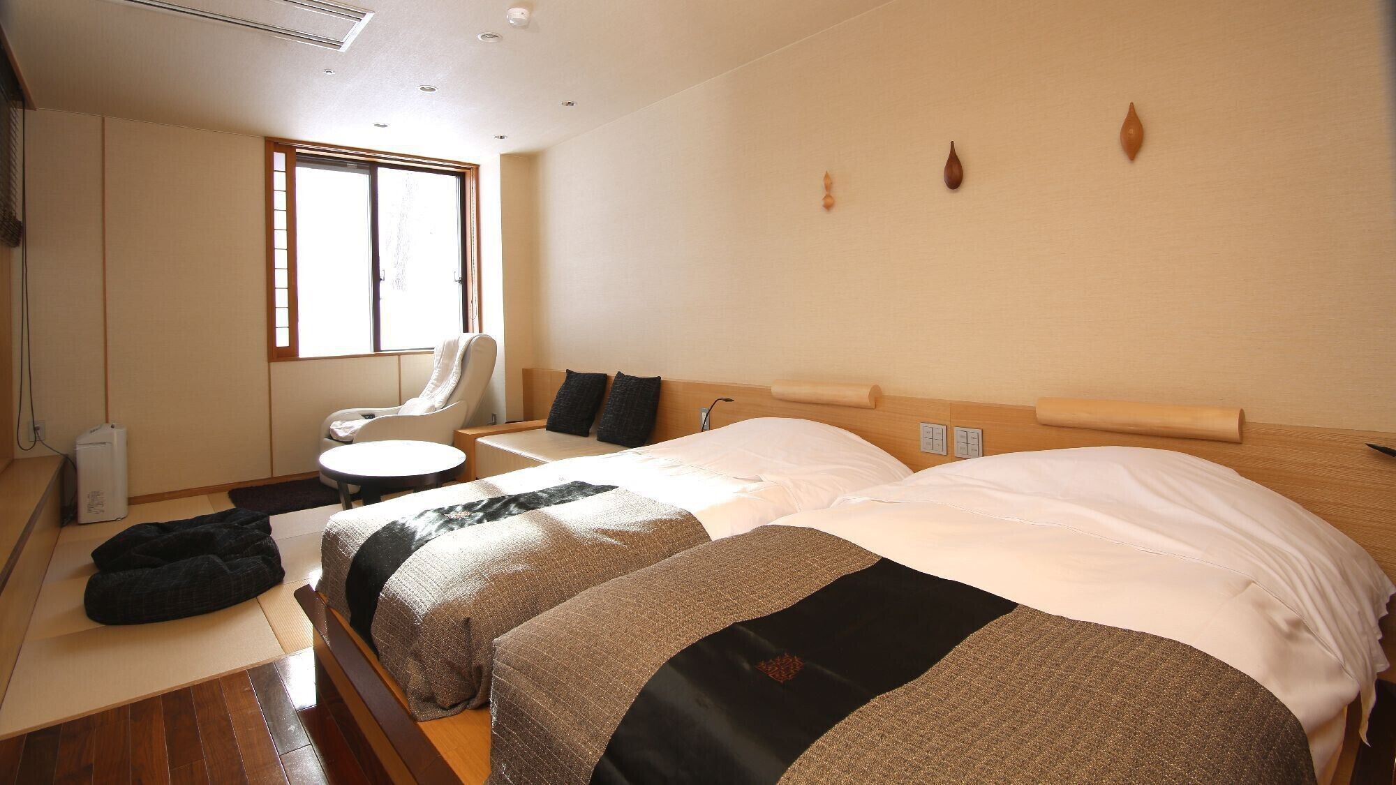 Une chambre d’hôtel avec deux lits, une chaise, une petite table et une fenêtre.