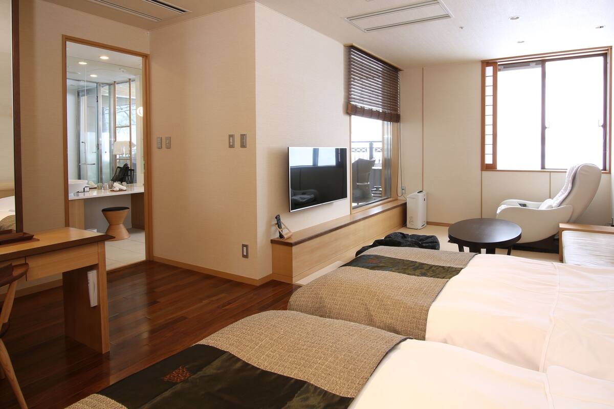 Hotellihuone, jossa on sänky, työpöytä, tuoli, televisio ja ikkuna.