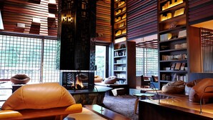 A modern interior with a fireplace, leather seating, bookshelves, and a stone accent wall. - Niseko Konbu Onsen Tsuruga Besso Moku No Sho (Niseko)