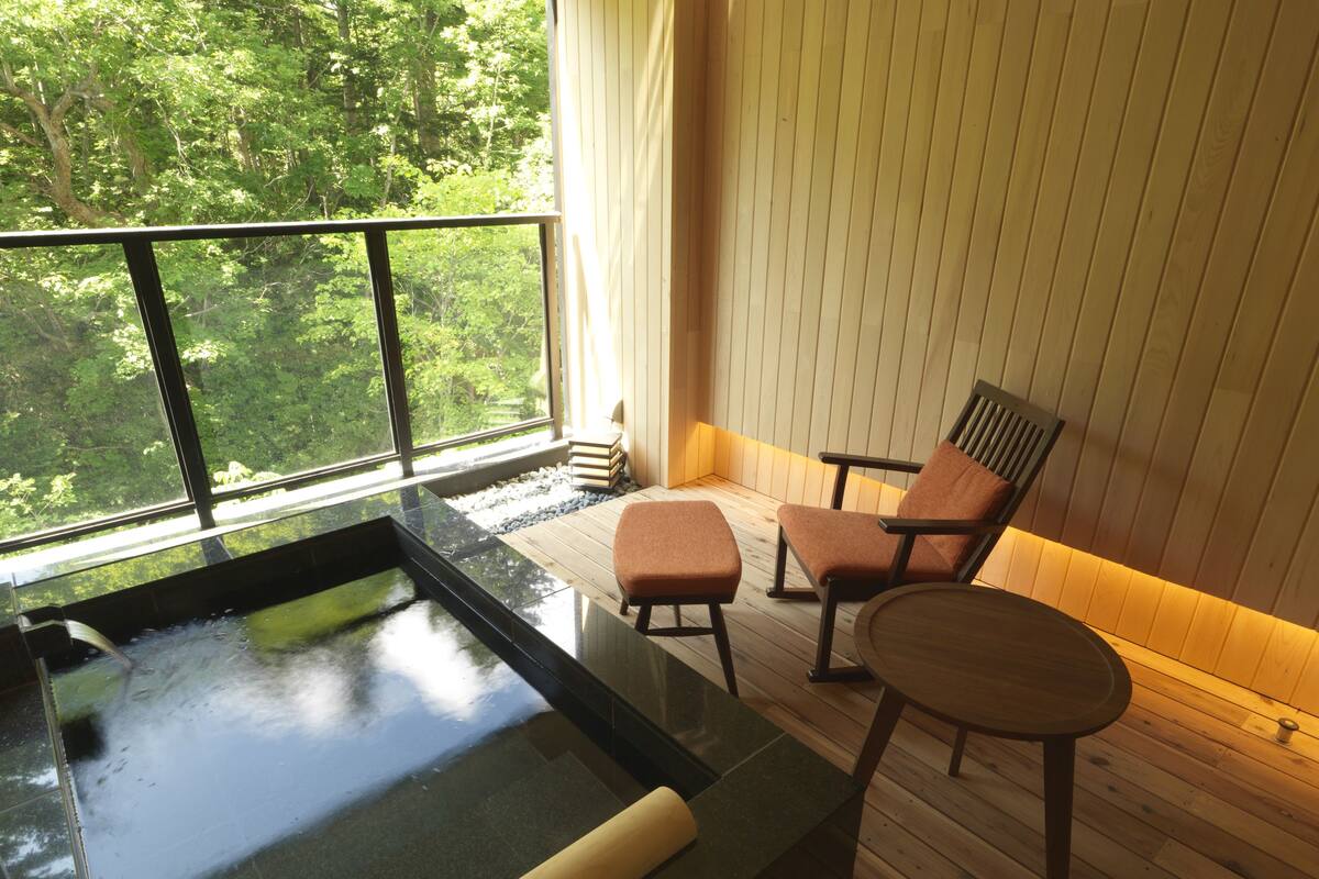 Ein Wellnessbereich mit Whirlpool, Holzboden und zwei Sesseln.