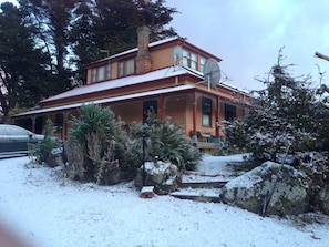 A two-story house with a red roof and a chimney, surrounded by snow-covered ground and trees. - AAA Granary Accommodation (Promised Land)