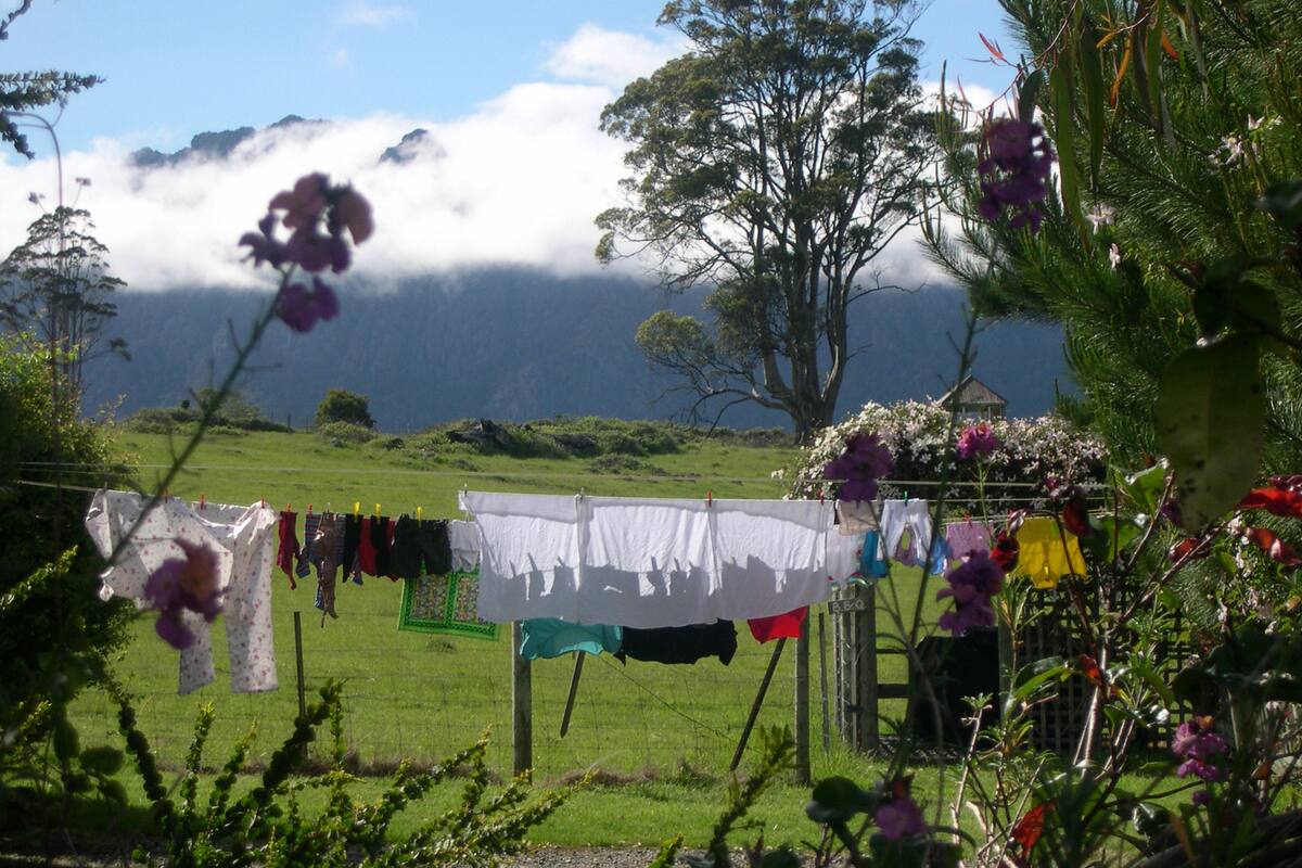 Paisaje rural con un tendedero y una casa al fondo.