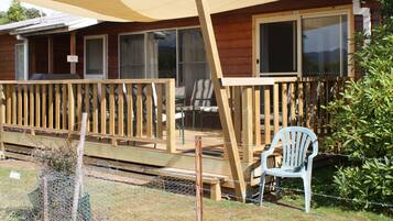 A wooden house with a covered porch, a chair, and a fence.