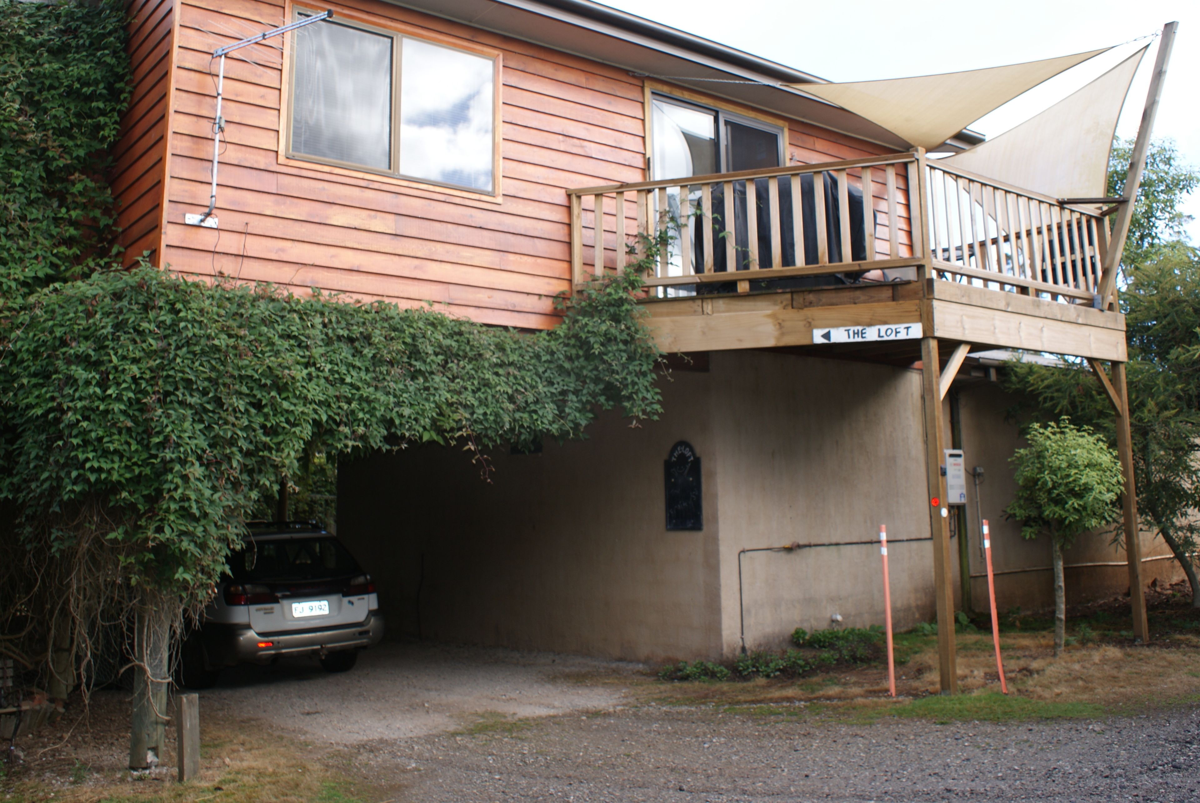 A two-story wooden house with a balcony, a garage, and a sign indicating 'The Loft'.
