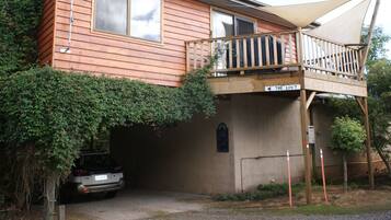 A two-story wooden house with a balcony, a garage, and a sign indicating 'The Loft'.