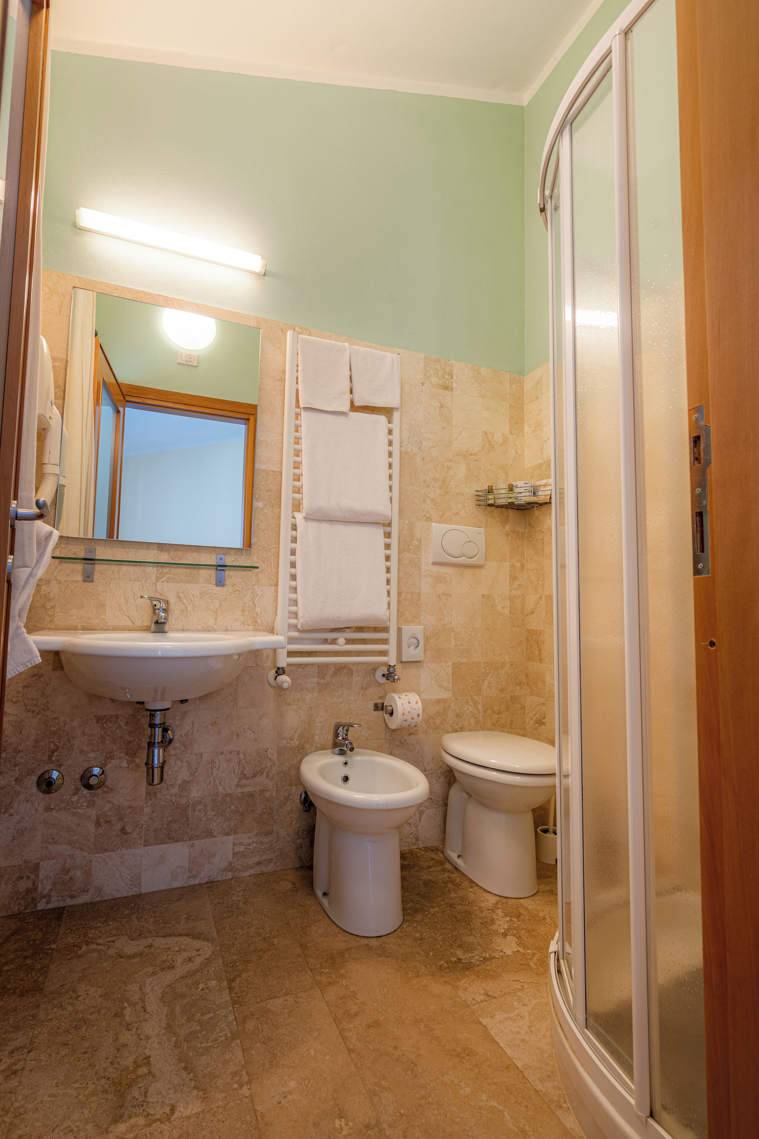 A bathroom with a sink, bidet, toilet, and a glass-enclosed shower.