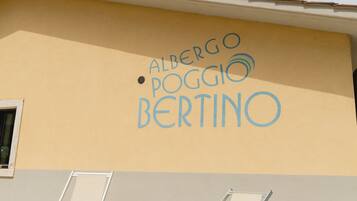 Ein Gebäude mit beige-farbener Fassade und blauem Himmel. Auf der Wand ist
