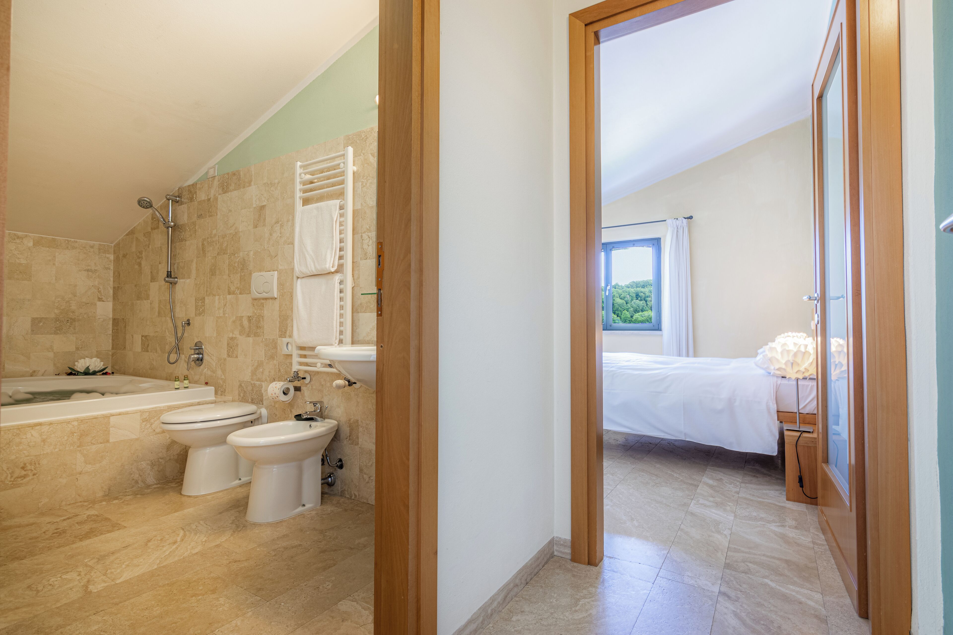 A modern bathroom with a bathtub, two toilets, and a bidet.