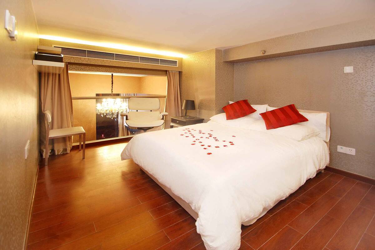 Une chambre d’hôtel avec un grand lit, un bureau, une chaise et un banc.