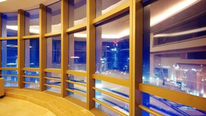 Interior moderno de hotel com grandes janelas e vista para a cidade.