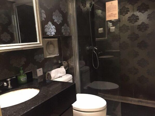 Une salle de bain avec un lavabo en marbre noir, des toilettes blanches et une douche à parois de verre.