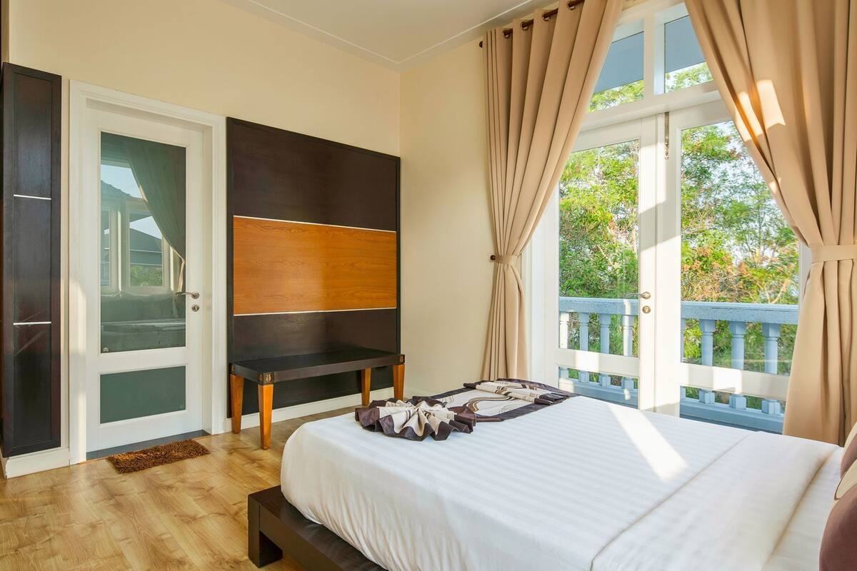 Ein Schlafzimmer mit Bett, Schreibtisch, Kleiderschrank und einem Balkon mit Aussicht.
