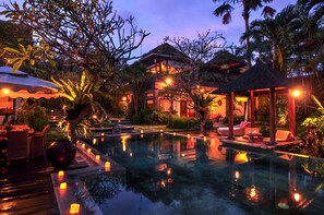 Un espace piscine paisible, doté de chaises longues et d’un belvédère, le tout entouré d’une végétation tropicale luxuriante.