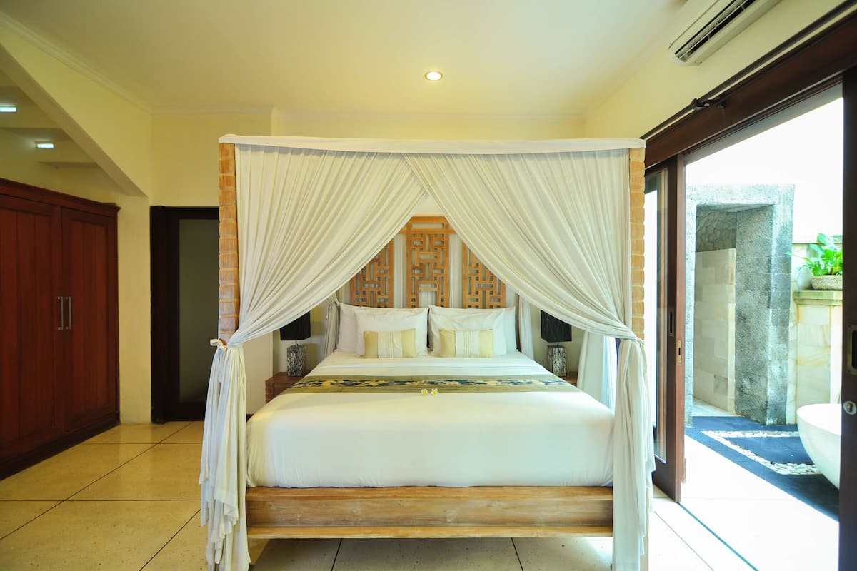 A four-poster canopy bed with white bedding, wooden headboard, and bedside tables with lamps.