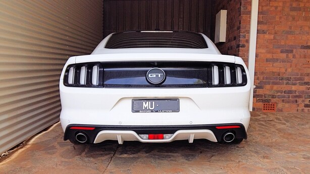 A white Mustang GT with a license plate reading "MU" parked in a garage. - Capon Cottage (Broken Hill)