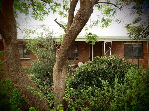 A brick building with a visible door labeled "CAPON" and a window with a metal screen. - Capon Cottage (Broken Hill)