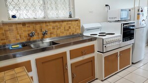 A kitchen with a sink, stove, microwave, and refrigerator. - Capon Cottage (Broken Hill)