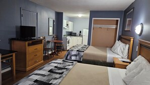 A hotel room with two beds, a desk with a television, a kitchenette, and a bathroom. - Metro Inn (Victoria)