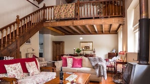 A spacious living room with a wooden staircase, a fireplace, and a dining area with a table set for a meal. - Clare Valley Heritage Retreat (Clare)