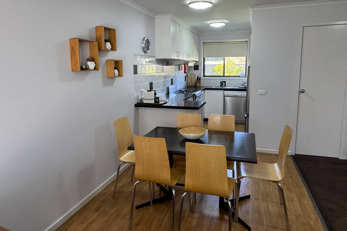 Una cocina moderna con comedor, armarios de madera y una ventana.