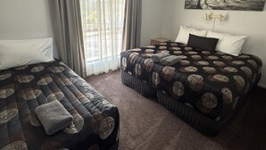 A hotel room with two beds, a window with curtains, an air conditioning unit, and a painting on the wall. - Barwon Valley Lodge (Belmont)