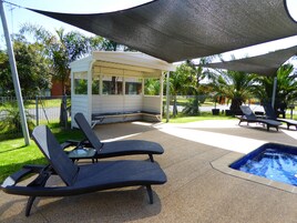 Una piscina al aire libre, sombrillas, sillones reclinables de piscina