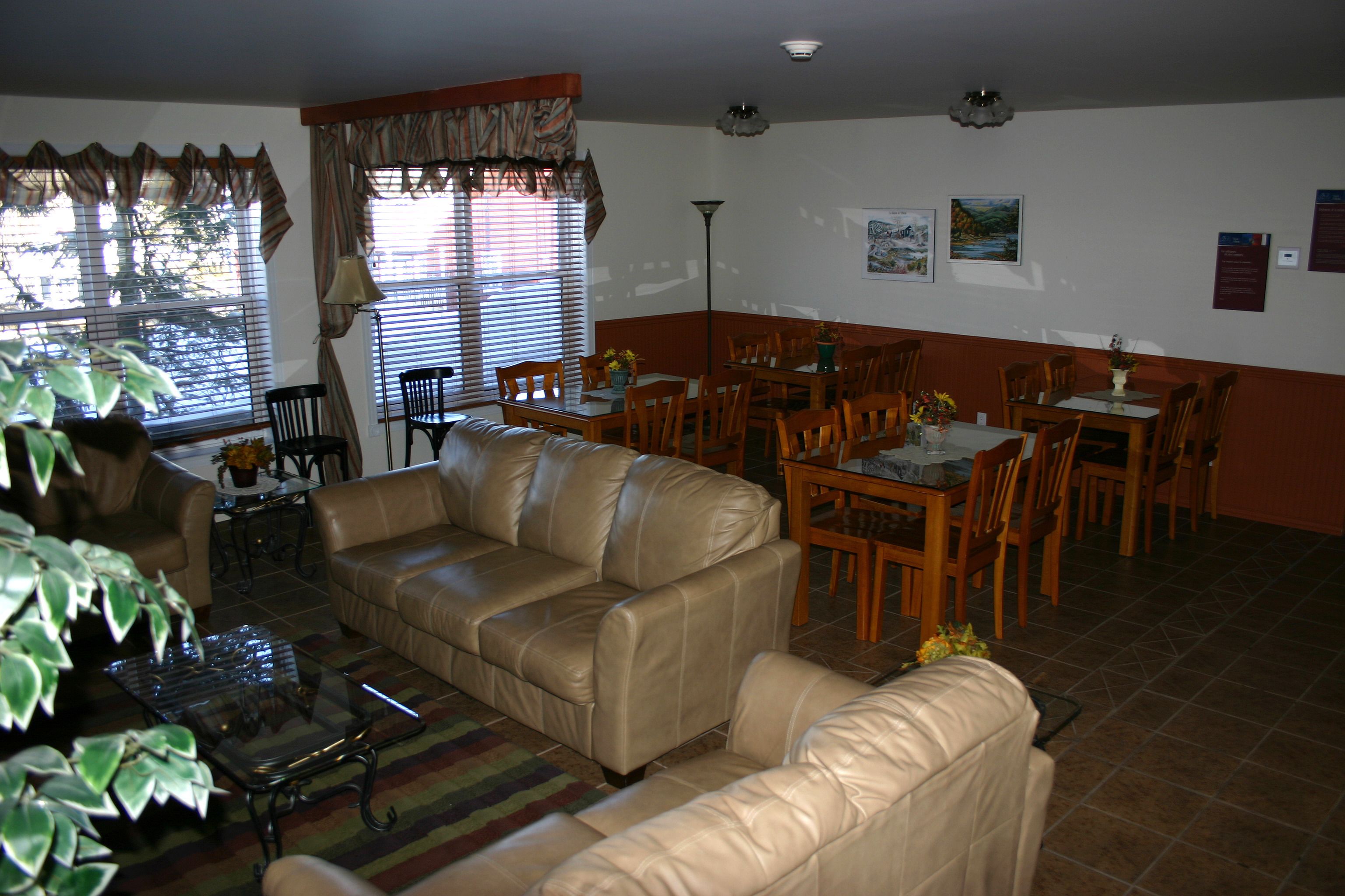A living room with a beige leather sofa, dining table, chairs, and a coffee table.
