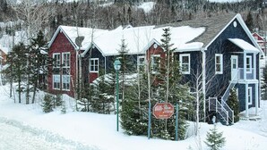 A row of snow-covered houses with a sign indicating 'Vibron' and 'Porte du Nord'. - Maison de Vébron (L'Anse-Saint-Jean)