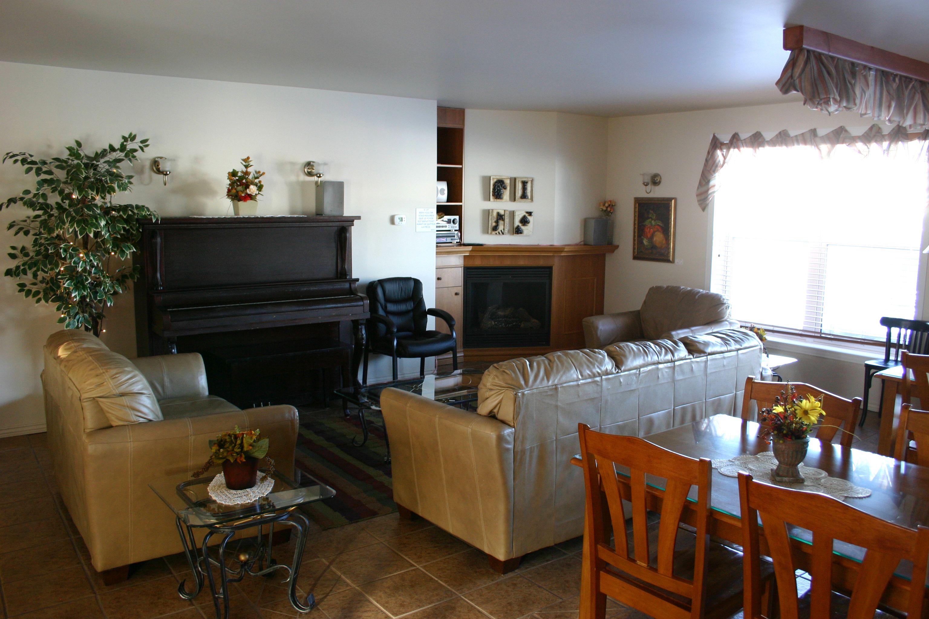 A living room with a piano, sofas, a dining table with chairs, and a fireplace.