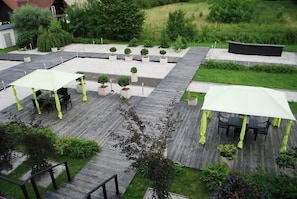 Ein Dachgarten mit Holzterrasse, Kübelpflanzen und Sitzbereichen im Freien.