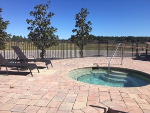Relax by the pool surrounded by a brick-patterned walkway and lush greenery.