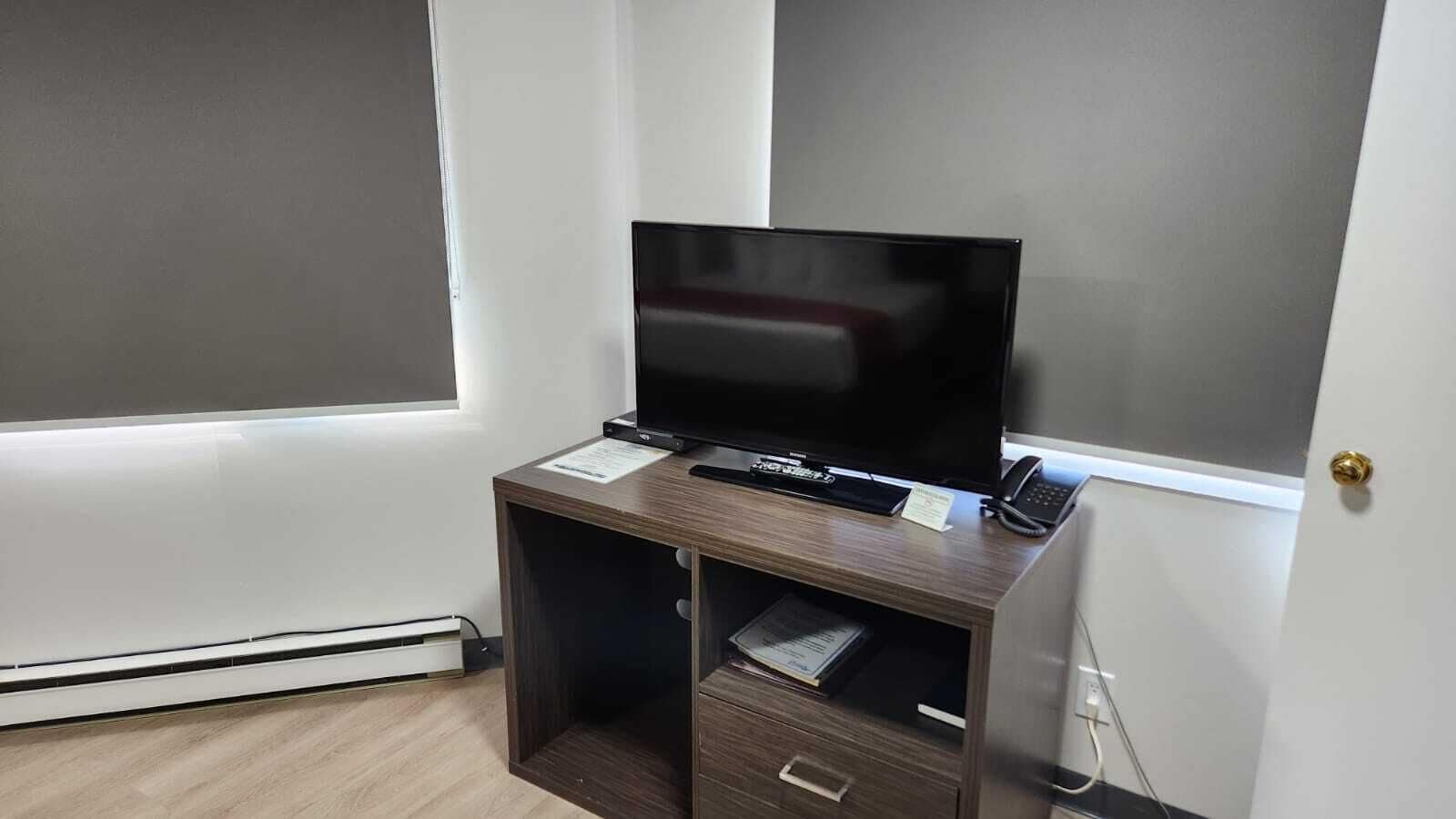 A small, dark wood desk with a flat-screen TV, a phone, and a small cabinet.