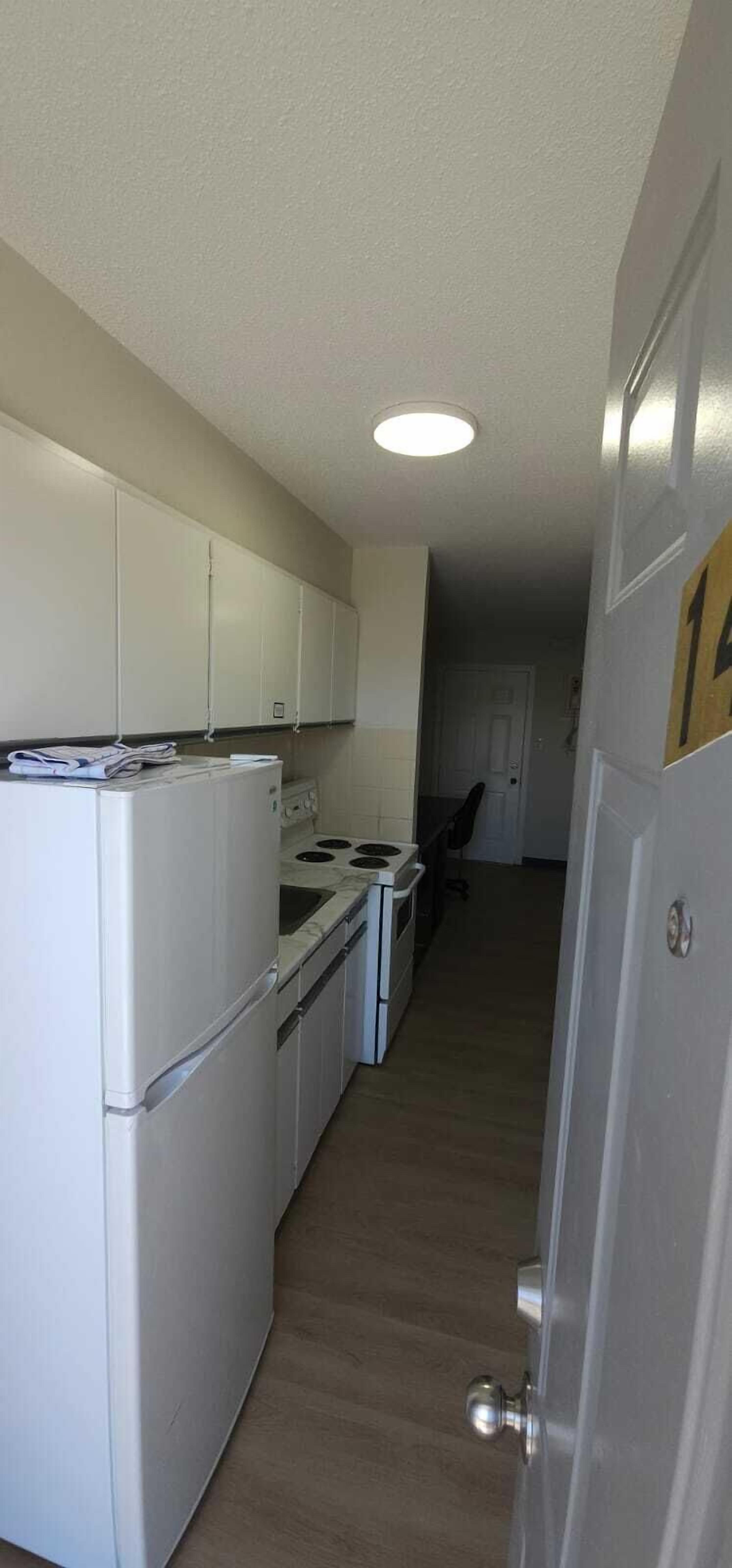 A compact kitchen with white appliances, a stove, and cabinets.