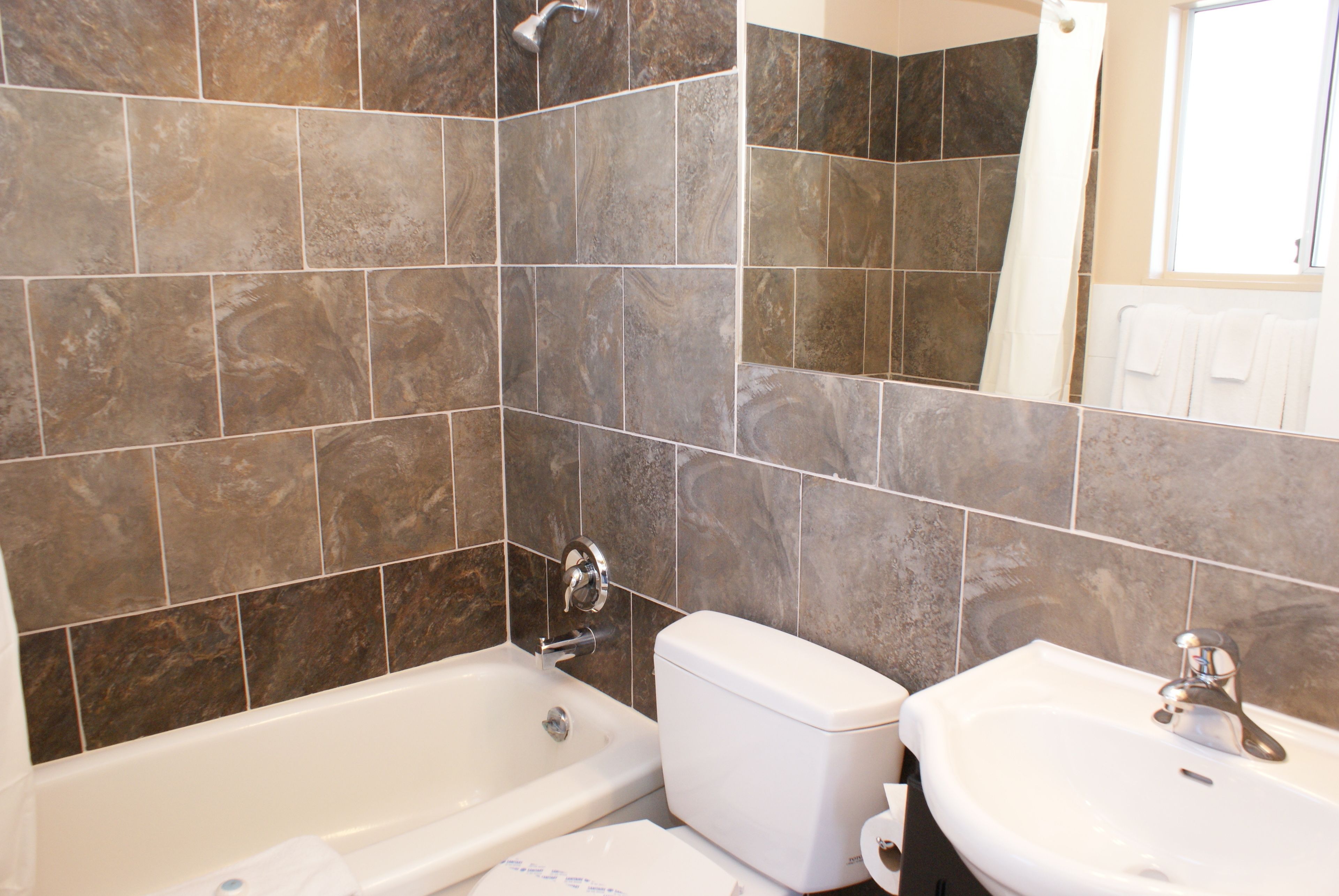 A bathroom with a bathtub, toilet, and sink, all with white fixtures.