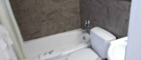 A bathroom with a bathtub, toilet, and sink.