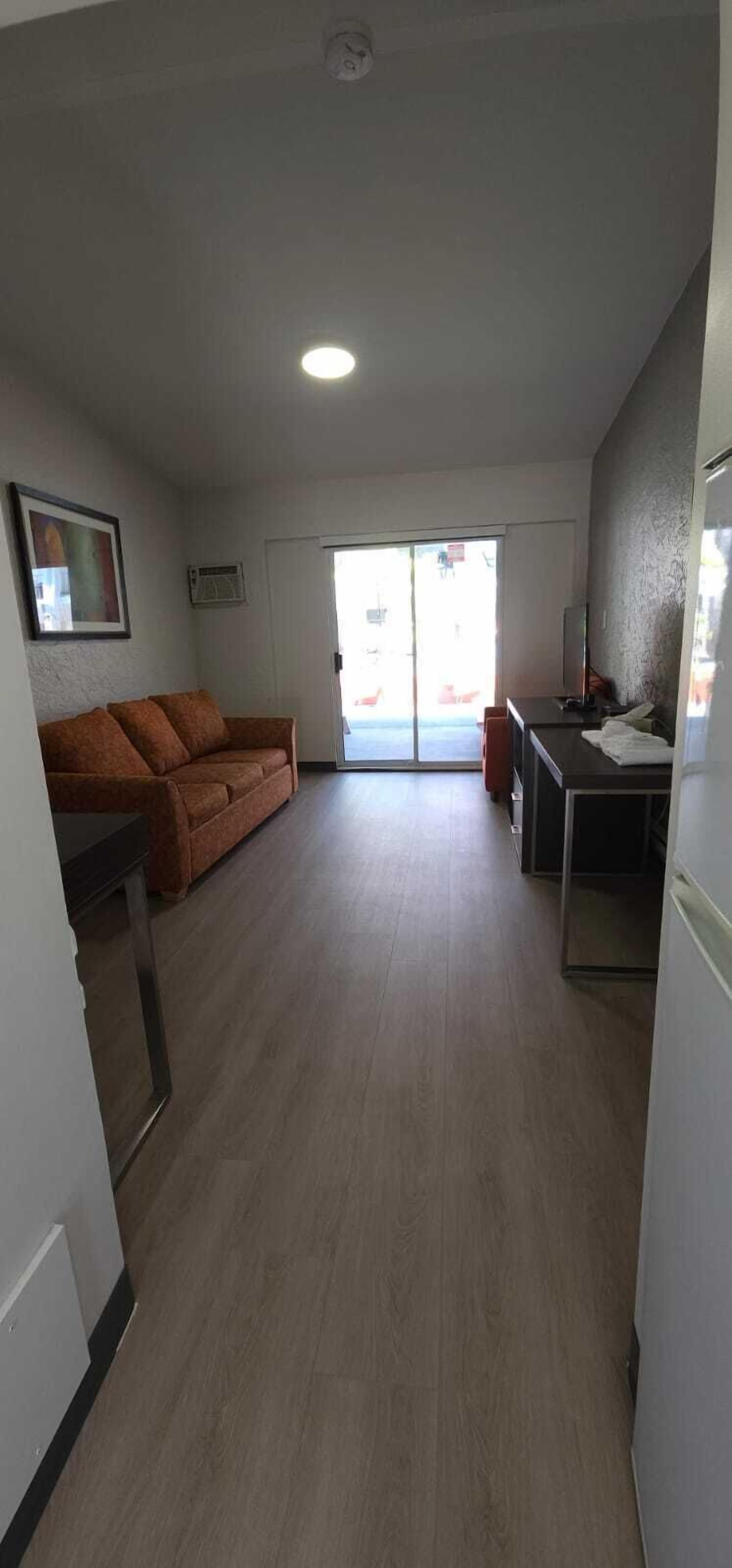 A spacious living area with a sofa, a small table, and a kitchenette.