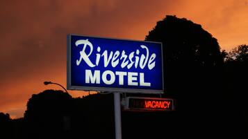 Segnaletica di motel con la scritta 'Riverside Motel' e un cartello con la dicitura 'Nessuna camera disponibile'.