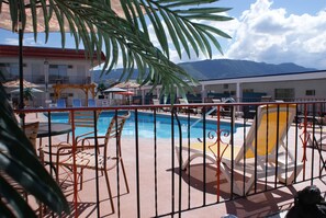 A pool area with lounge chairs and a view of mountains.