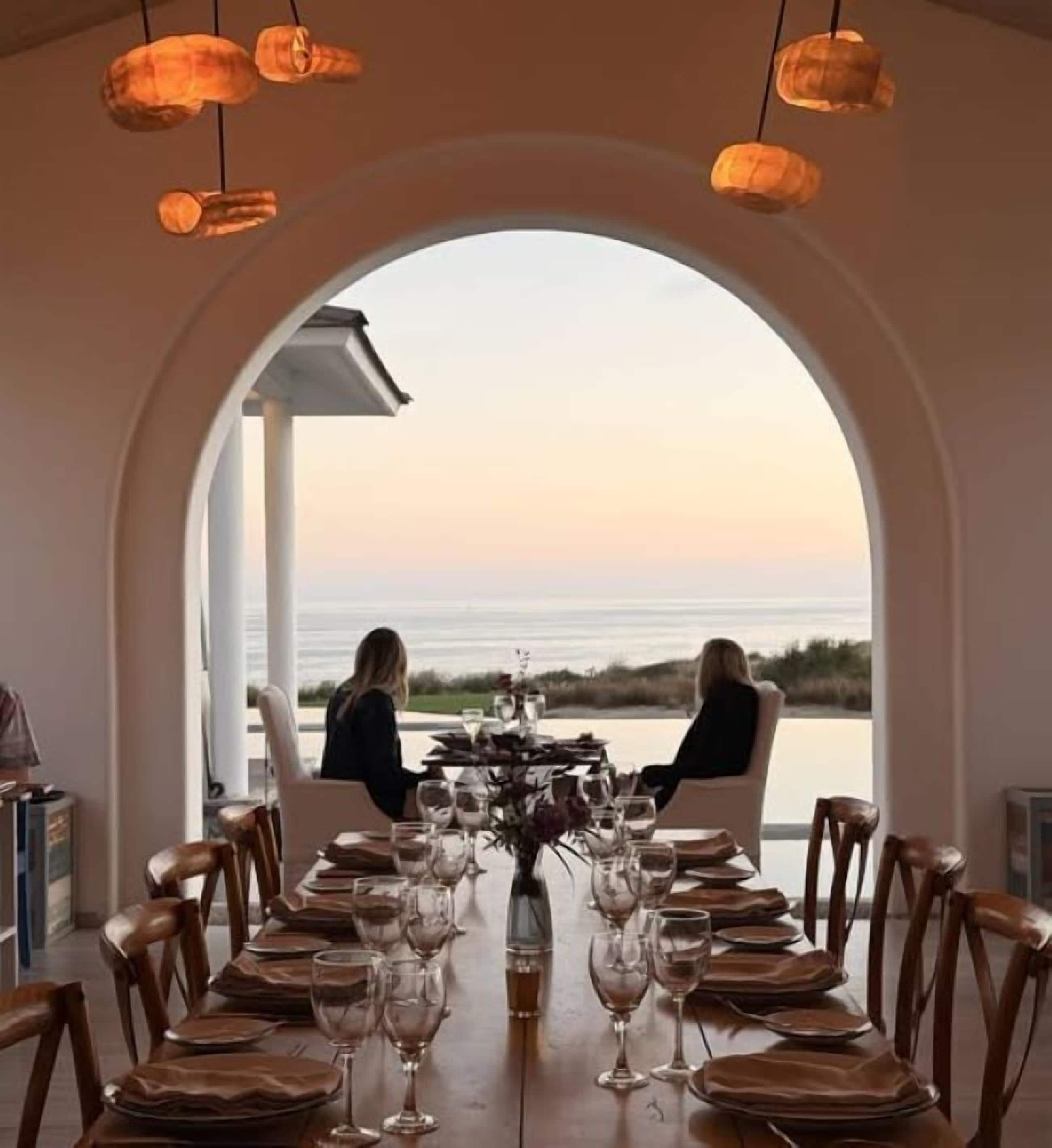 A dining table set for two with a view of the ocean.
