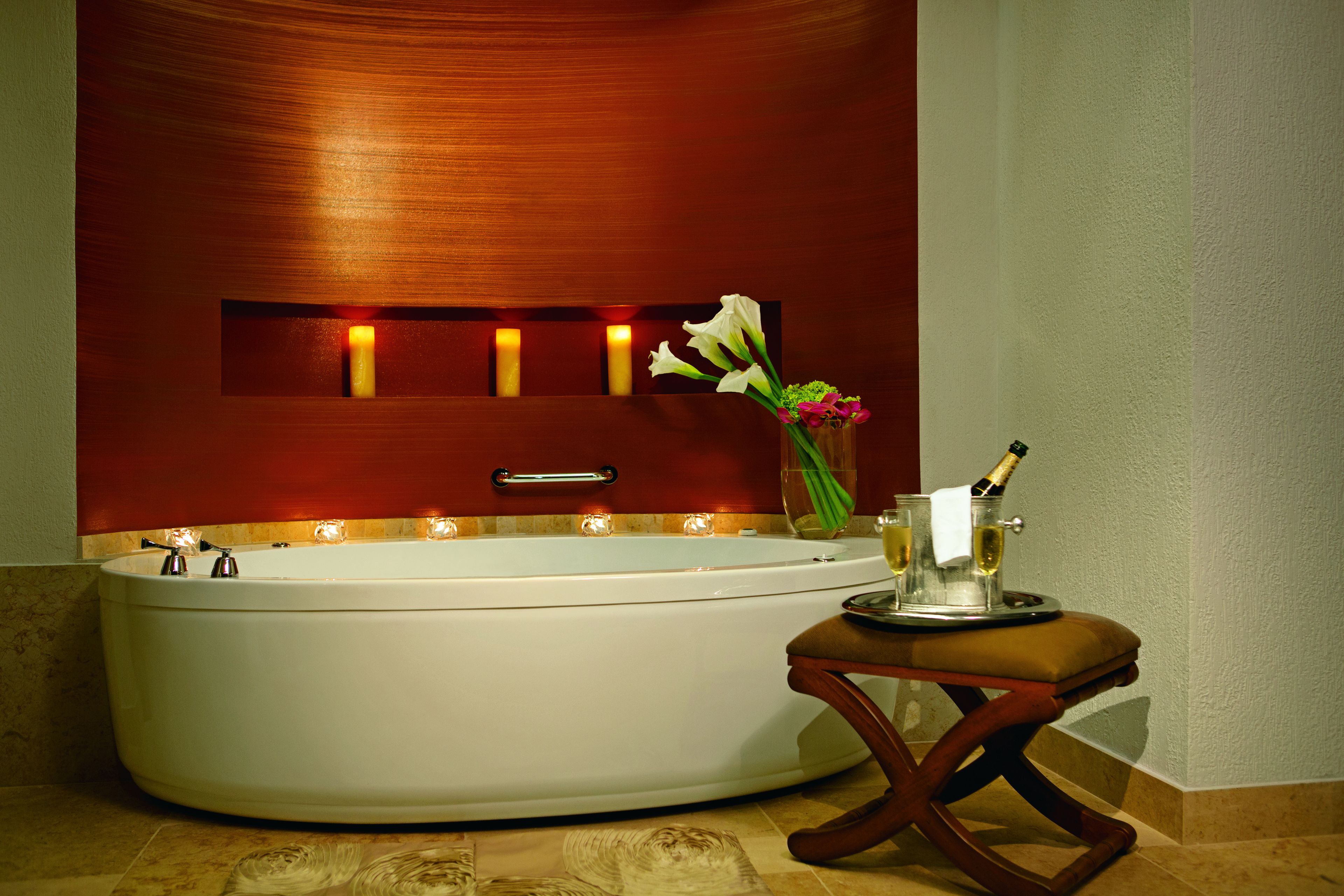 A modern bathroom with a freestanding bathtub, a vanity with a mirror, and a small table with a bottle of champagne and a glass.