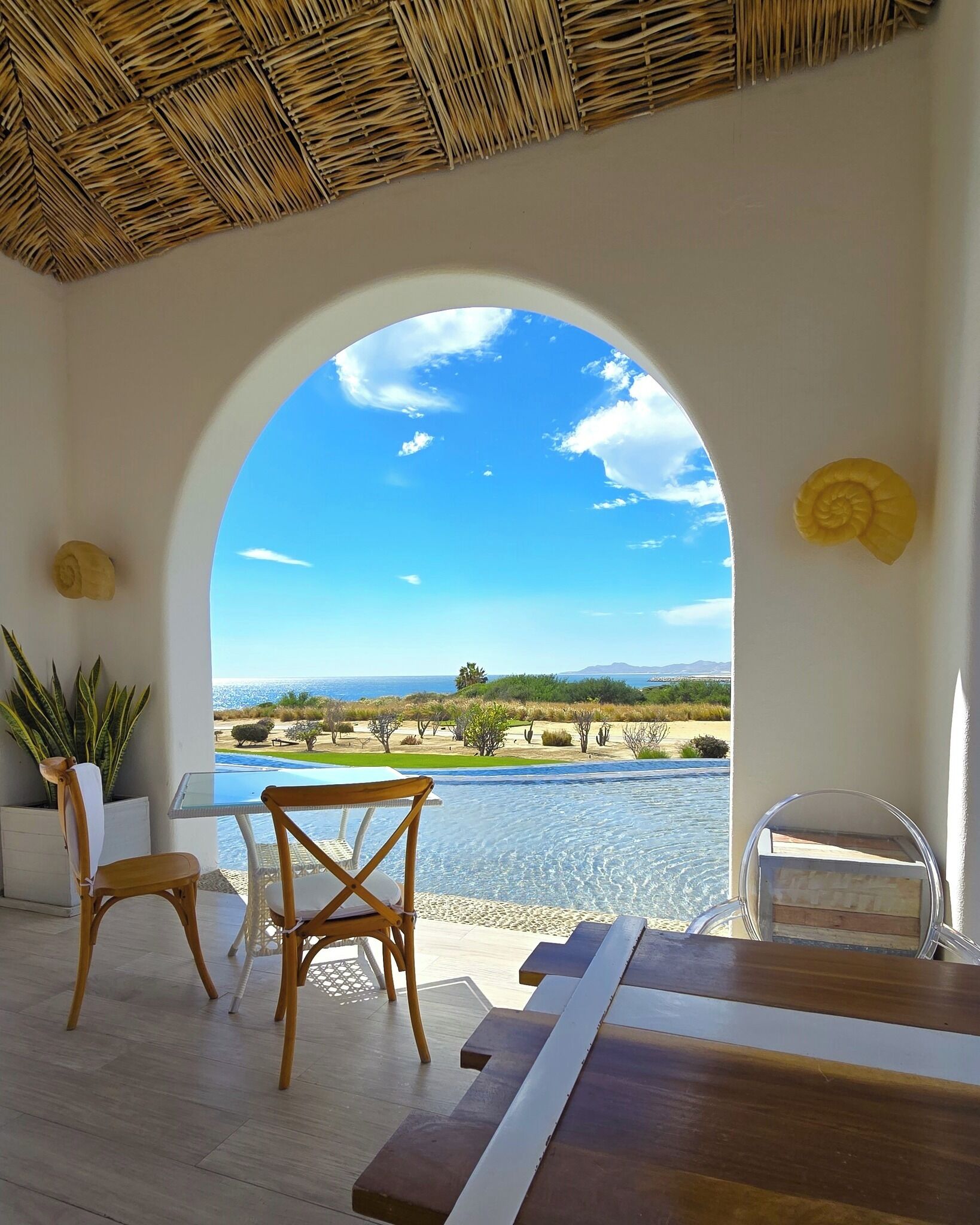 A room with a large arched window overlooking a pool and landscape.