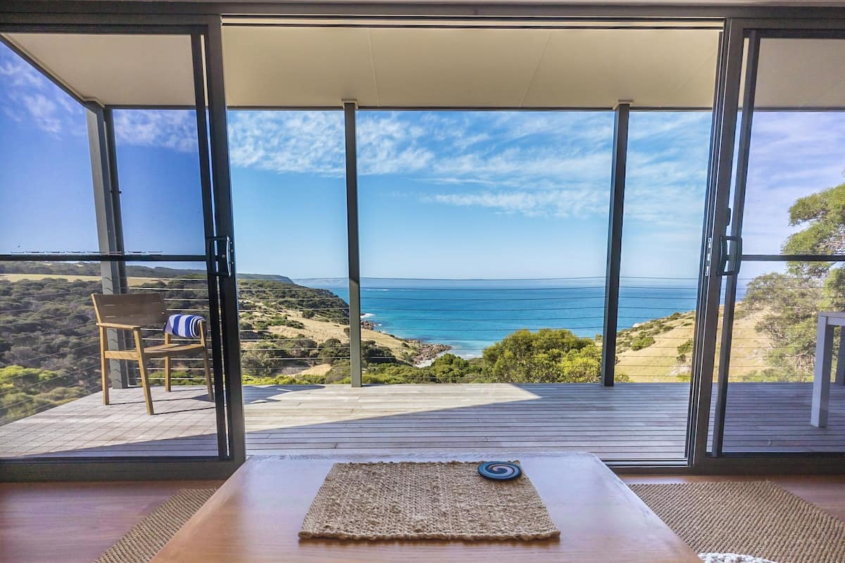 Un balcon avec vue sur l’océan et les collines.