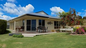 A two-story house with a covered patio, large windows, and a sign indicating it is a holiday home. - Searenity Holiday Accommodation (Emu Bay)