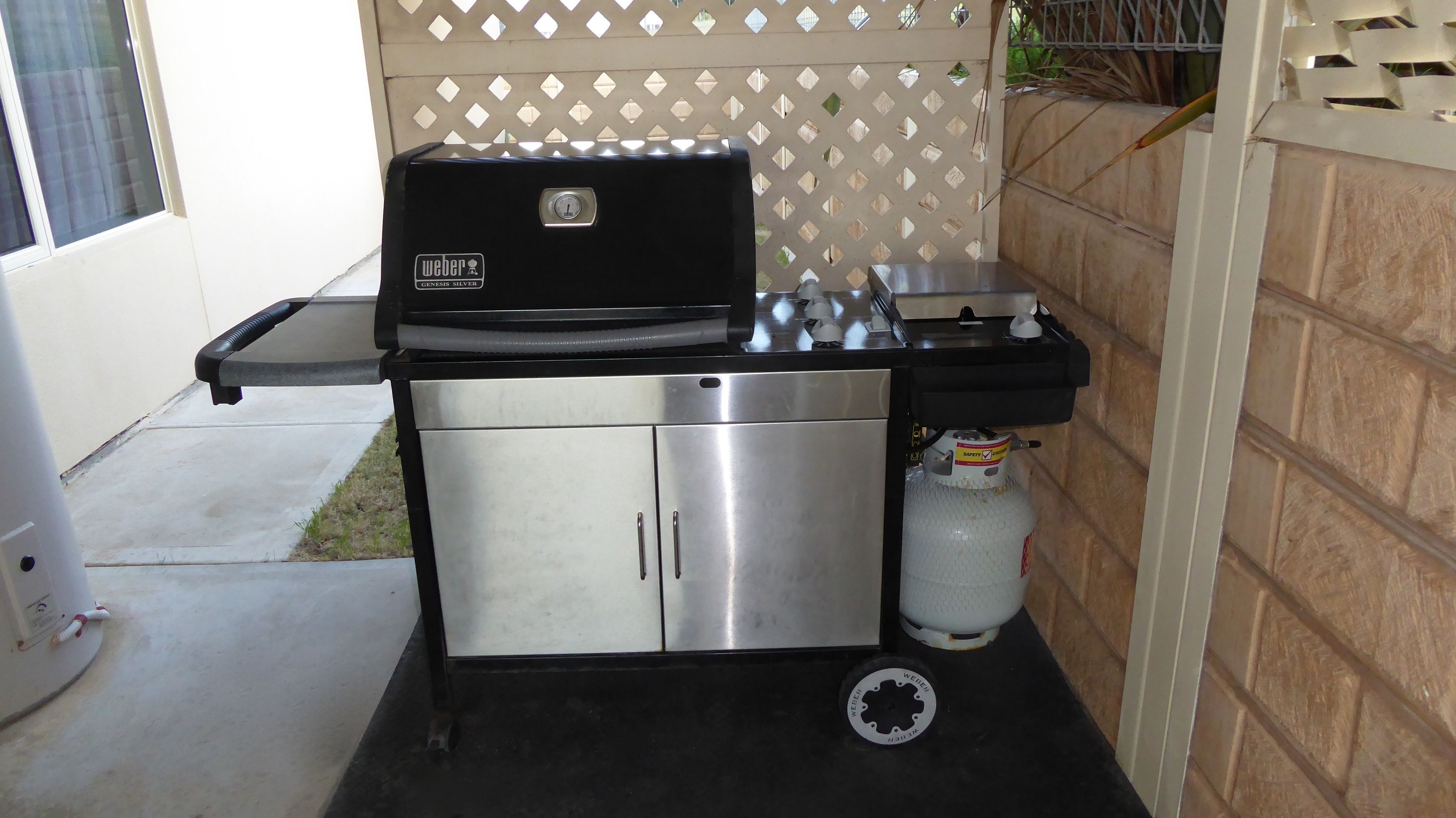 A compact, stainless steel kitchen with a built-in grill, a gas cylinder, and a small sink.