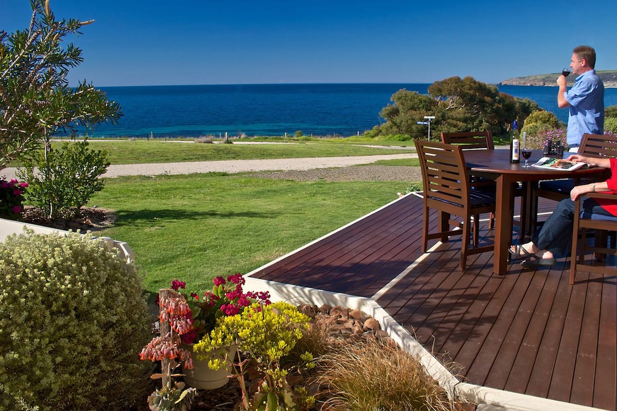 A deck with a table and chairs overlooking a coastal landscape.